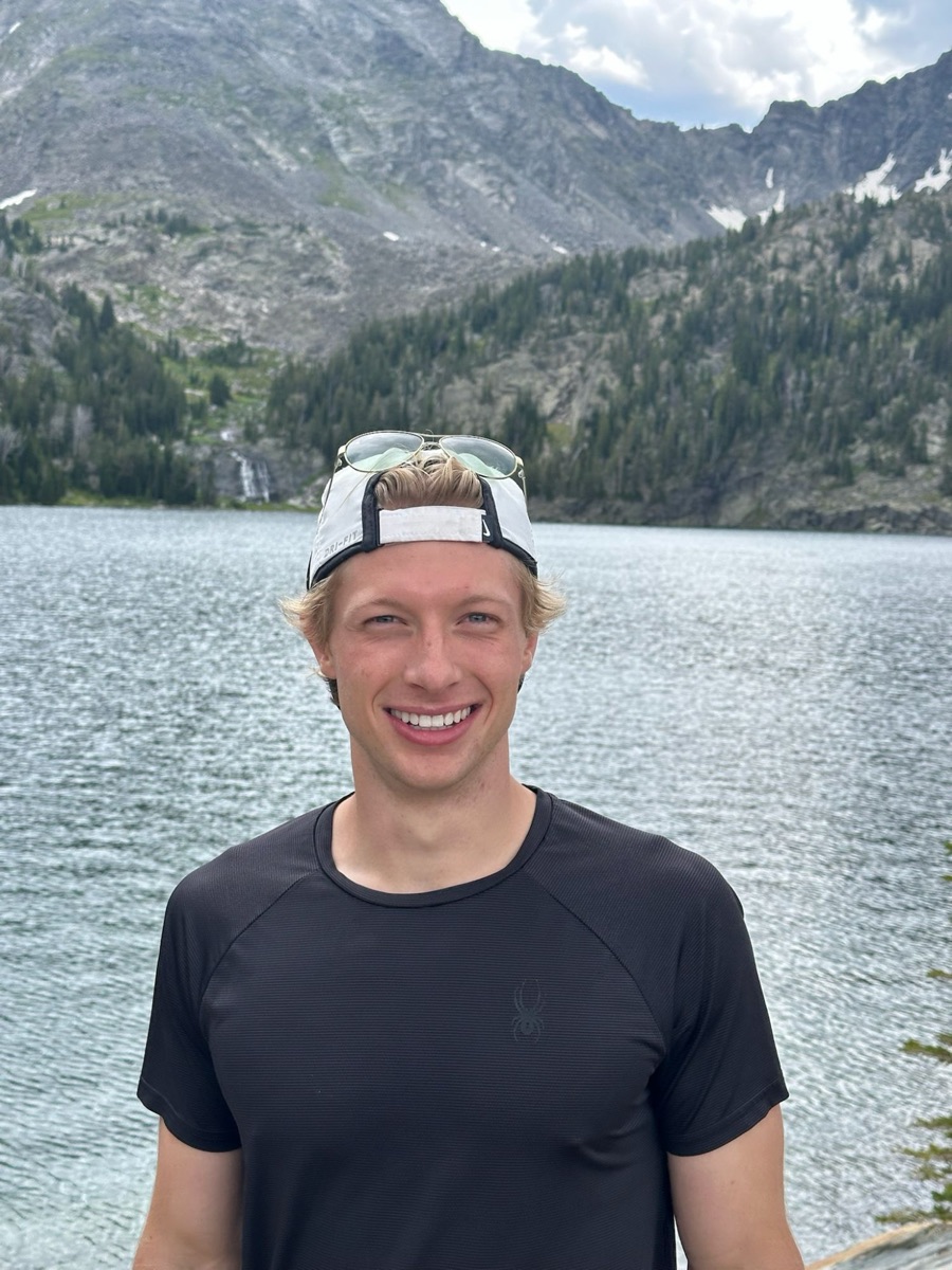 Standing in front of an alpine lake below a steep rocky ridge in the mountains near Bozeman