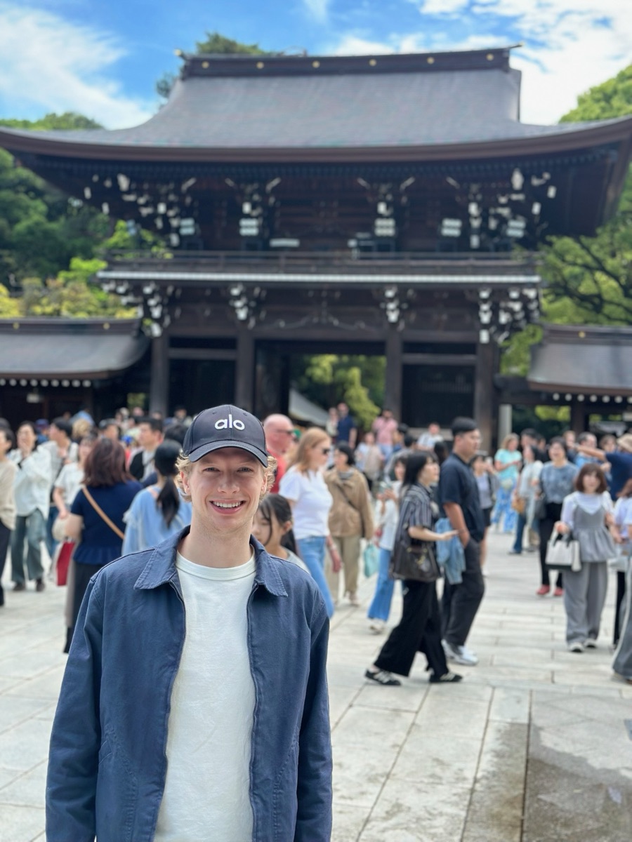 Standing on the approach to the Meiji Shrine in Tokyo, crowds moving past the gate behind